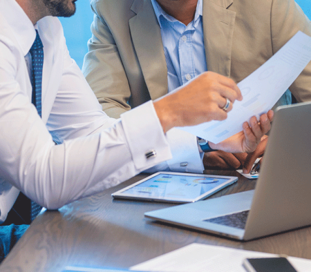 A Group Of People Sitting At A Table Looking At A Paper
