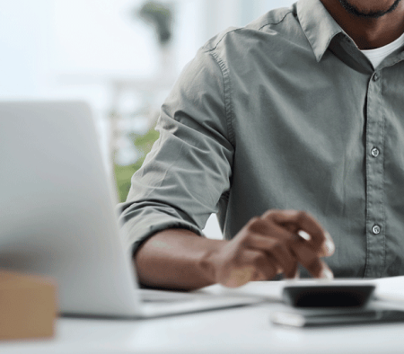 A Man Sitting At A Table Using A Laptop