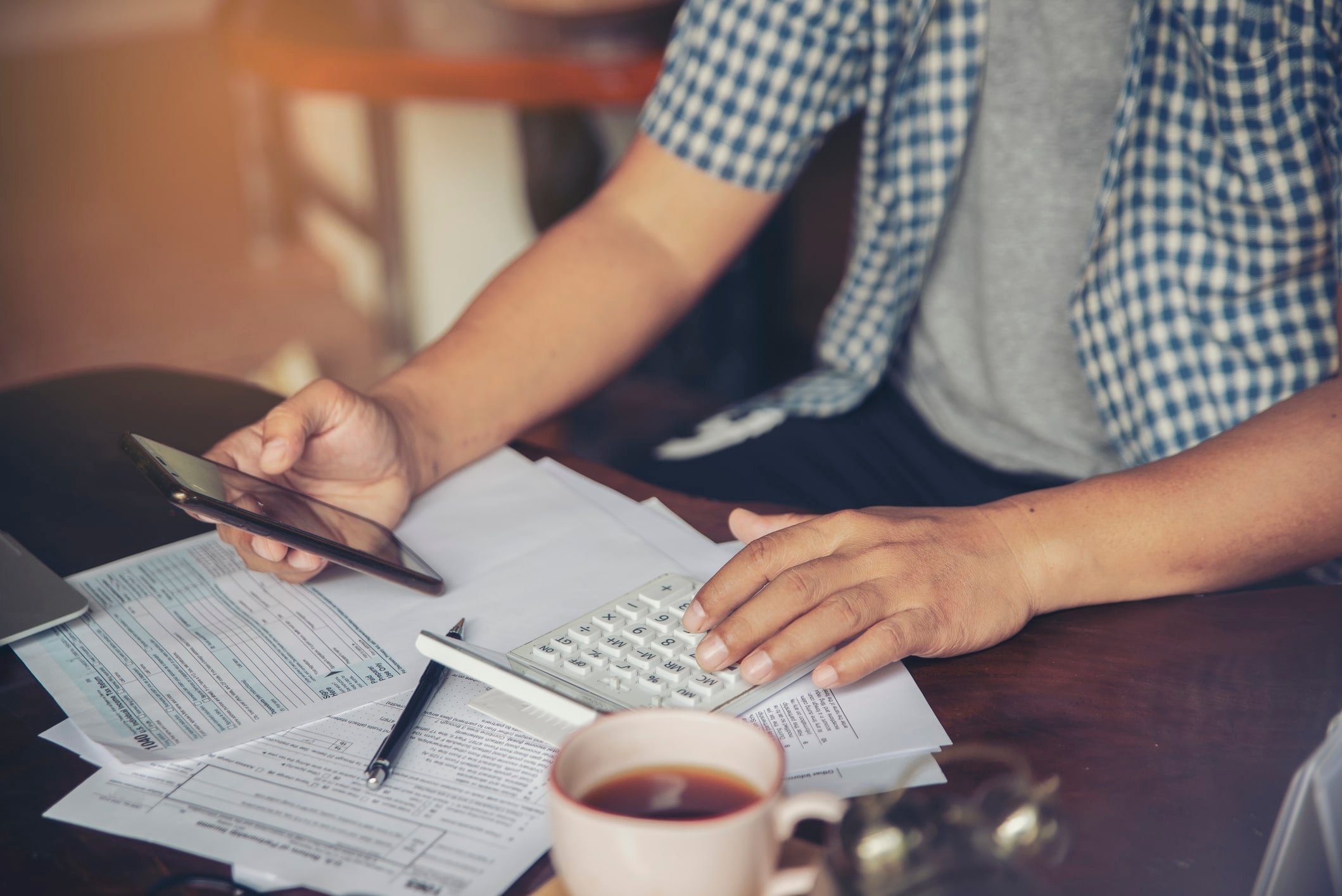 A person trying to contact the IRS by phone while looking over tax documents
