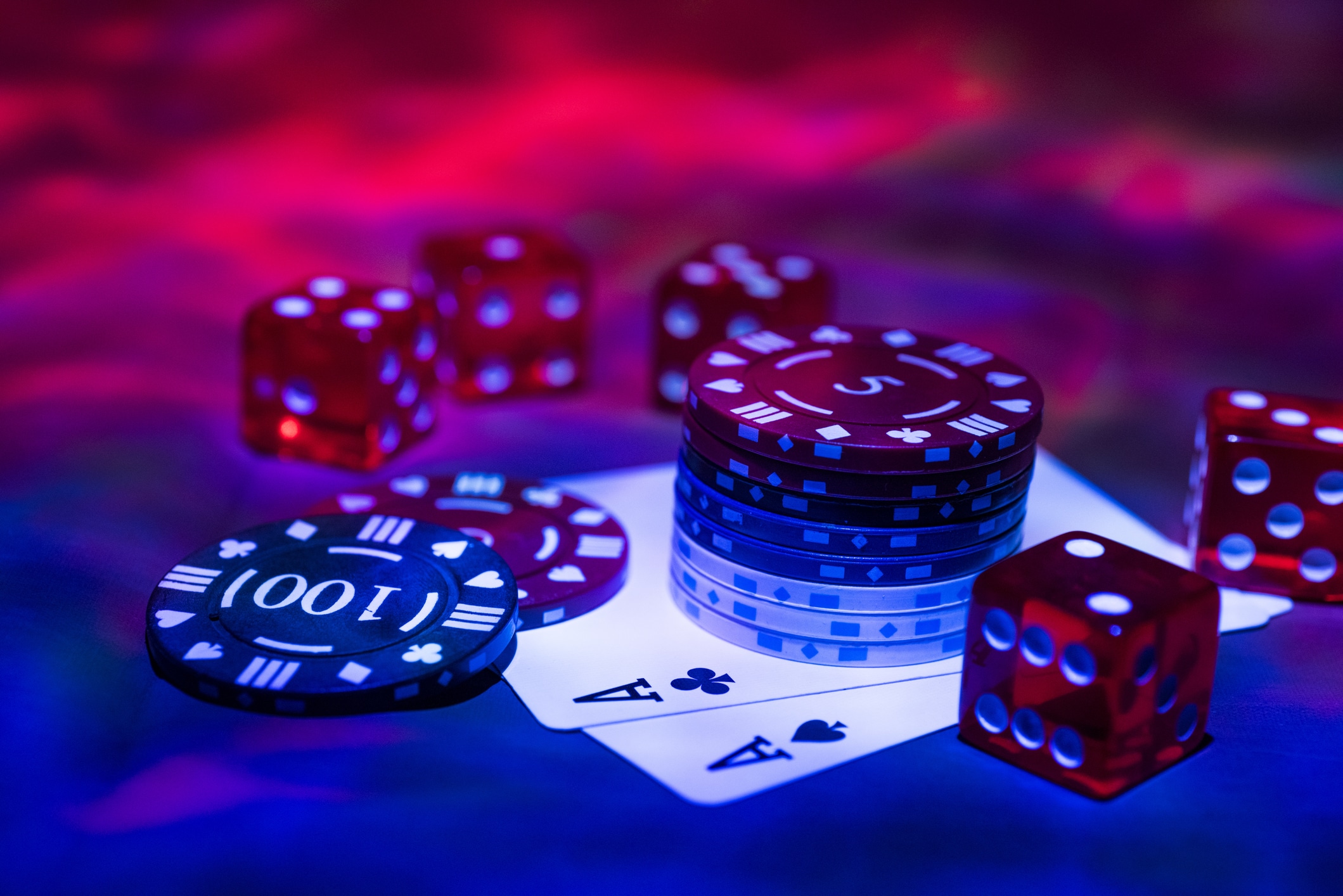 Poker chips, dice, and cards on a red & blue background